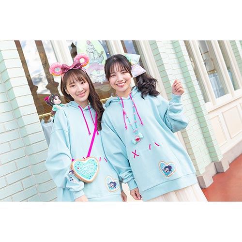Two people wearing matching light blue hoodies with cartoon designs in an outdoor setting.
